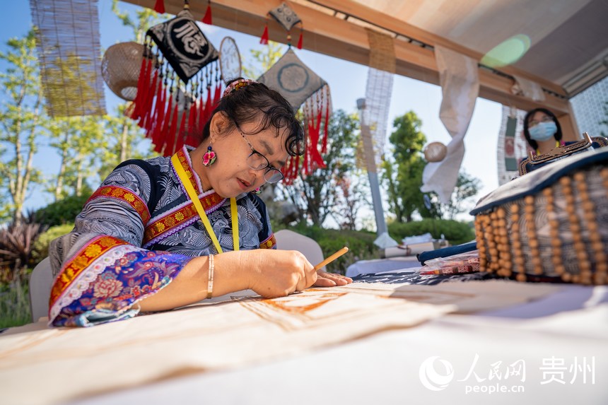 山地生活消費(fèi)與非遺傳承展現(xiàn)場，非遺技藝蠟畫傳承人展示蠟畫技藝。人民網(wǎng) 涂敏攝