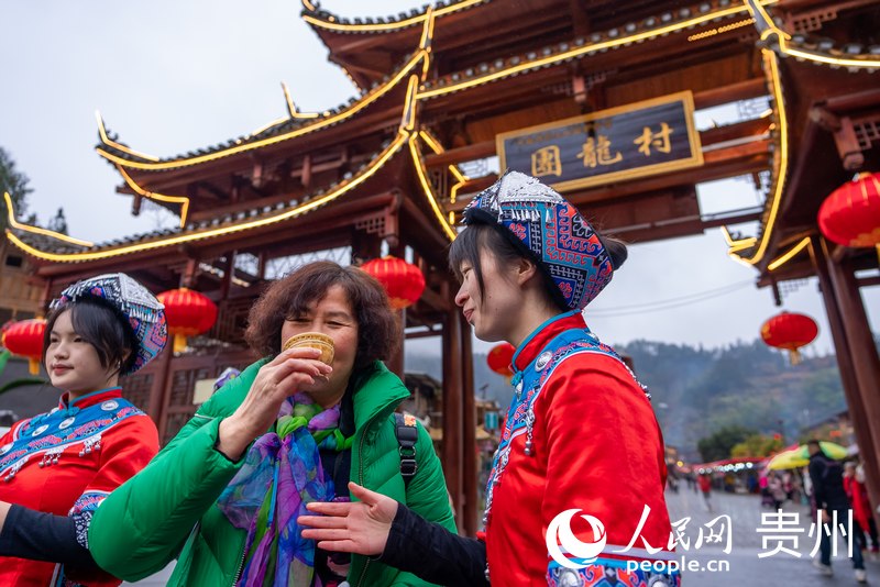 團(tuán)龍村“幸福土家過趕年”活動現(xiàn)場，游客品嘗攔門酒。人民網(wǎng)記者 涂敏攝