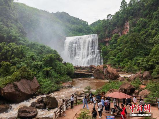 5月27日，游客在赤水丹霞旅游區(qū)·赤水大瀑布前游玩拍照。