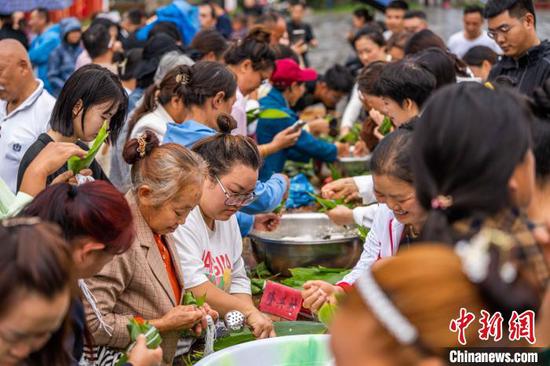 6月7日，在貴州省黔西市新仁苗族鄉(xiāng)化屋村，游客體驗(yàn)包粽子。