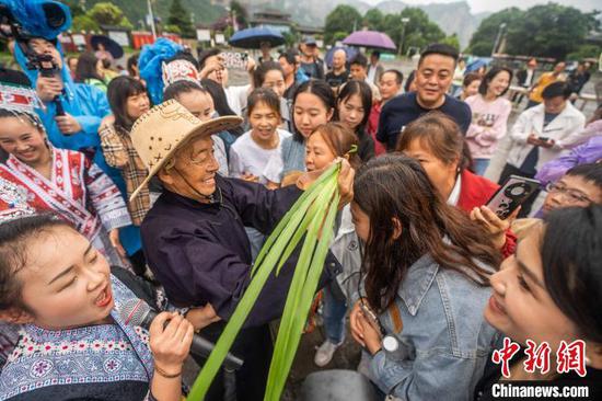 6月7日，在貴州省黔西市新仁苗族鄉(xiāng)化屋村，村民為游客點(diǎn)雄黃酒。